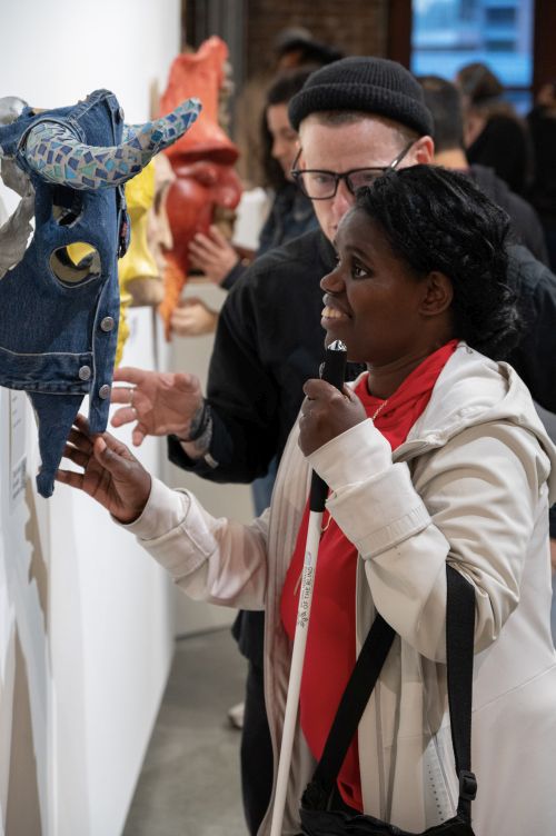 A visitor feels one of the masks at the Please Touch exhibition